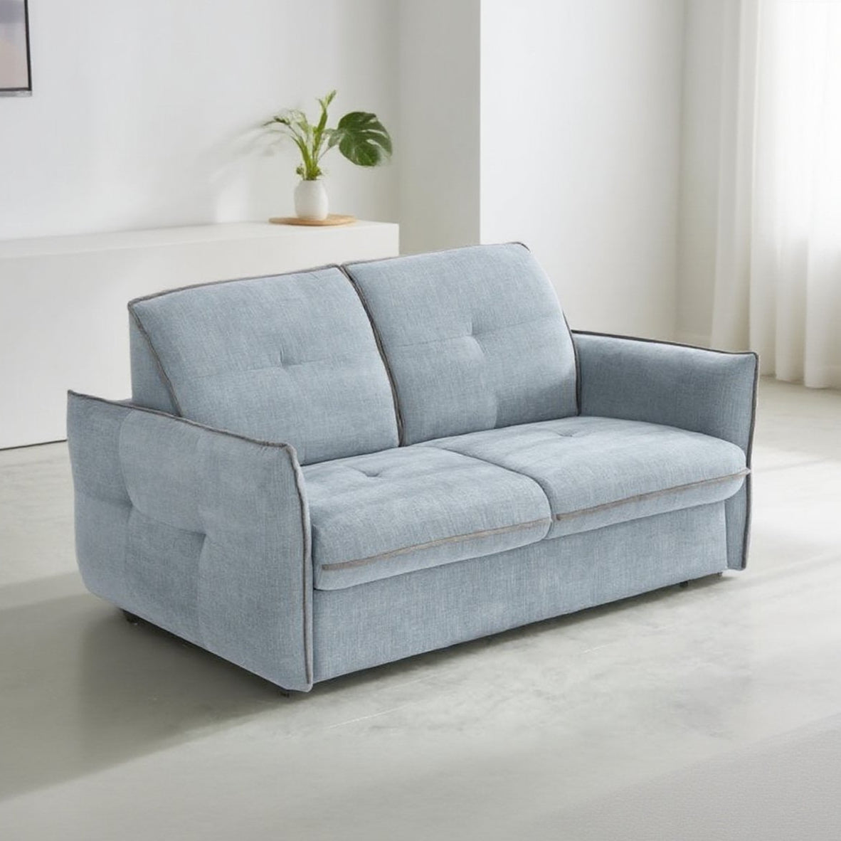 Canapé convertible en tissus bleu ciel, avec des accoudoirs fins, pour un maximum d'espace